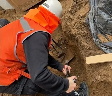 Técnico con casco y chaleco trabajando en una excavación